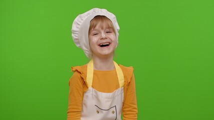 Wall Mural - Child girl dressed cook chef baker in apron and hat laughing out loud after hearing funny joke, feeling positive carefree amused isolated on chroma key background. Cooking school, children education