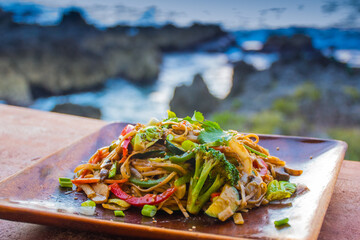 Wall Mural - A healthy vegetable Pad Thai served on a wooden plate. This vegan dish is to be eaten in natural surroundings