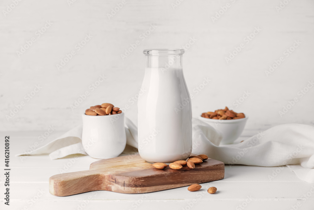 Bottle of tasty almond milk on light background