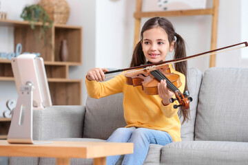 Wall Mural - Little girl taking music lessons online at home