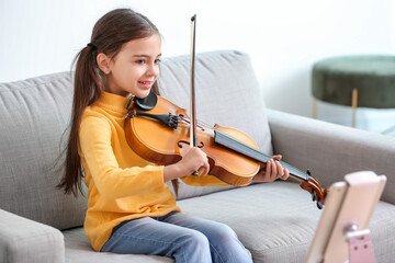 Wall Mural - Little girl taking music lessons online at home