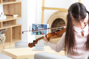 Wall Mural - Little girl studying music with her friend online at home