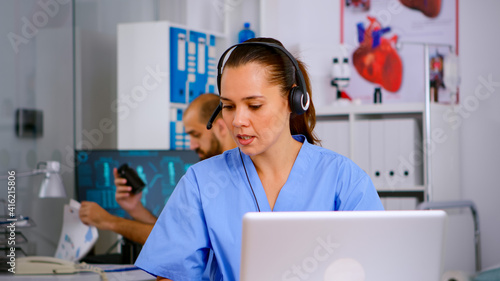 Specialist doctor nurse with headphones checking appointment during telehealth communication in hospital. Healthcare physician in medicine clinic, receptionist doctor assistant helping with