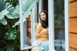 © Odua Images - beautiful asian woman drinking coffee in the morning by the window. view from outside.