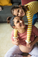 Wall Mural - Little girl hugging her pregnant mom.