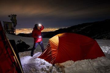 climber with headlamp near orange tent at night