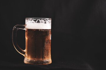 a pint full of beer and foam on a black background. alcoholic soft drink