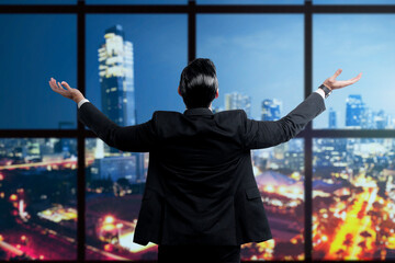 Wall Mural - Rear view of Asian businessman standing with raised hand