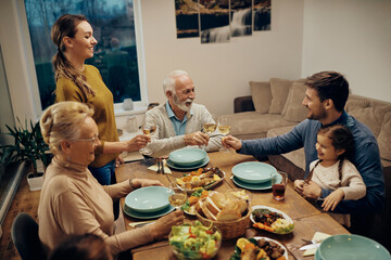 Senior man and his son toasting during family lunch at dining table.