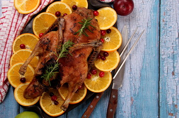 Baked whole duck with fresh rosemary and oranges on clay plate, Old blue wooden board background, Roast stuffed duck