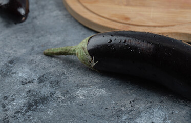 Close up photo of Fresh raw purple eggplant with wooden cutting board