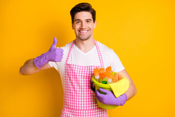 Sticker - Photo of young happy positive handsome man showing thumb-up hold bucket full of detergent isolated on yellow color background