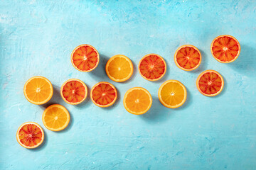 Wall Mural - Blood oranges and regular oranges, overhead flat lay shot on a blue background with copy space. Summer banner