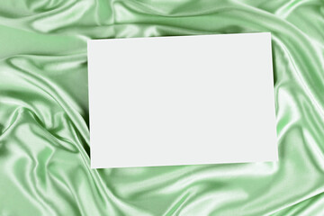 Canvas Print - Mock up blank white board canvas poster card for text greeting over draped green color silk cloth background. Top view