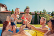 © Impact Photography - Friends eating watermelon popsicles and having fun at the swimming pool