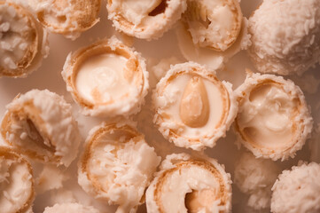 Cracked candy with almond and coconut flakes on white table closeup. Sweet tasty pastry. Top view.