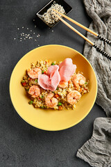 Canvas Print - Spicy Shrimp Fried Rice with Vegetables. Yellow plate with wooden chopstick on dark slate table. Chinese, asian, authentic food concept