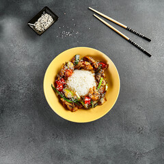 Canvas Print - Sweet and Sour Chicken and Vegetables with Rice. Stir Fry Chicken with Vegetables and Sesame. Yellow plate with wooden chopstick on dark slate table. Chinese, asian, authentic food concept