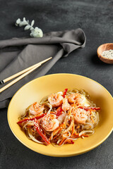 Canvas Print - Asian Stir Fried Shrimp and Rice Noodles. Sesame Rice Noodles with Shrimp in yellow plate with wooden chopstick on dark slate table. Asian, authentic food concept