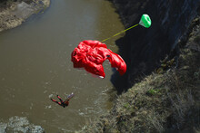 Basejumper Opens The Parachute At A Low Altitude After Jumping From A High Cliff Above The River. Basejumping.