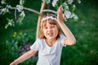 © bondarillia - Portrait of funny kid girl 5-6 year old holding flower standing in blossom spring garden