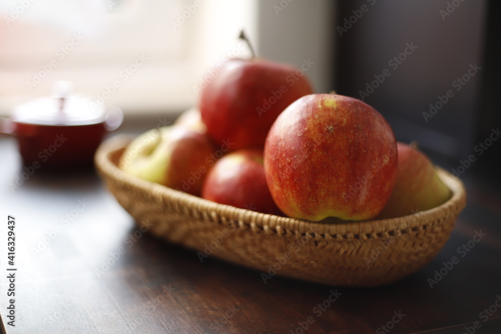 Jabłka czerwone w wiklinowym koszyku na drewnianym stole ciemnym - obrazy, fototapety, plakaty 