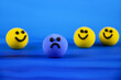 Blue sad ball and happy yellow balls stock images. Single sad blue smiley among happy yellow ones stock photo. Depressed ball on a blue background images
