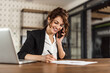 © bnenin - Woman writing some notes, while talking with someone over the phone.
