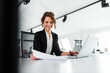 © bnenin - Portrait of a happy businesswoman looking at paper document and smiling.