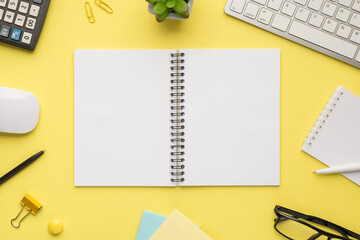 Photo overhead of notebook keyboard calculator pen computer mouse notes plant glasses and paper clips isolated bright color backdrop