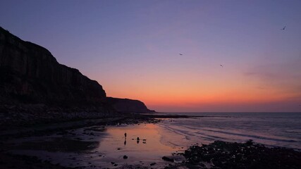 Wall Mural - An empty Hastings beach, with Hastings Pier in the background, Sussex, England at sunrise.