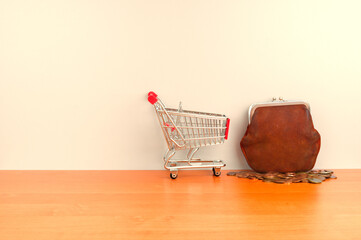 Business concept with trolley, cash money and purse on wooden background