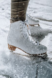 Young woman ice skating outdoors on a pond on a freezing winter day. Detail of skate shoes.
