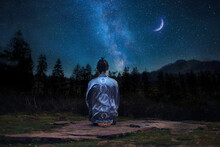 Young Man In Meditating On The Mountain Under A Starry Sky