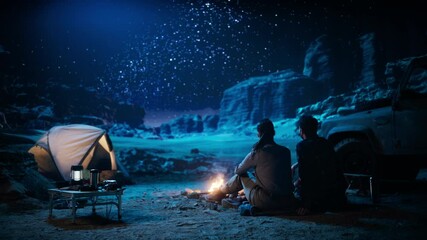 Wall Mural - Happy Couple Tent Camping in the Canyon, Sitting by Campfire Watching Night Sky with Milky Way Full of Bright Stars. Two Travelers In Love On a Romantic Vacation Trip. Zoom Out Back View Shot