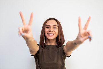 Wall Mural - cheerful smiling woman going crazy on white background showing peace sign