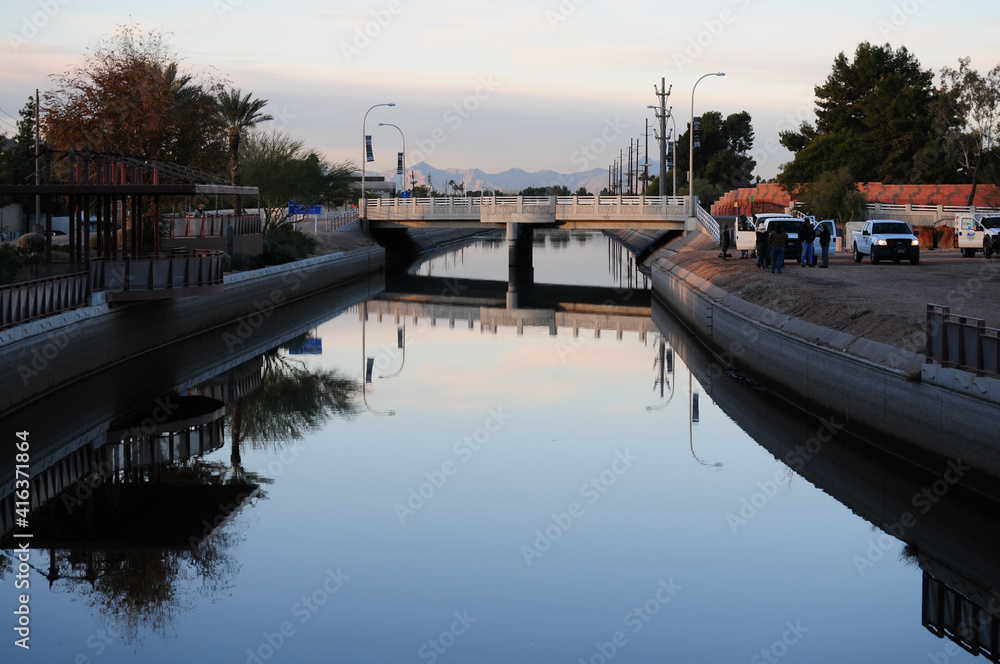Urban canal with concrete embankments and bridge overpass, reflecting ...