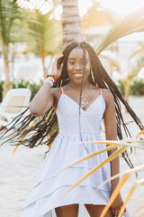 cheerful african american young woman having fun on the beach at sunset