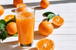 Ripe bio oranges and a glass of fresh squeezed orange juice on white wooden background. Organic Sicilian oranges.