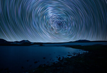 Wall Mural - beautiful small lake and mountains under the colorful star trails on the sky. night time lapse photo