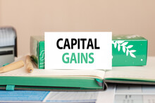Business Concept Sheet Of White Paper For Notes With Text CAPITAL GAINS. Notebook, Pen, Stamp On The Yellow Background.