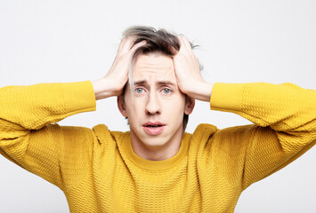 Young handsome man wearing yellow sweater over isolated background suffering from headache desperate and stressed because pain and migraine.