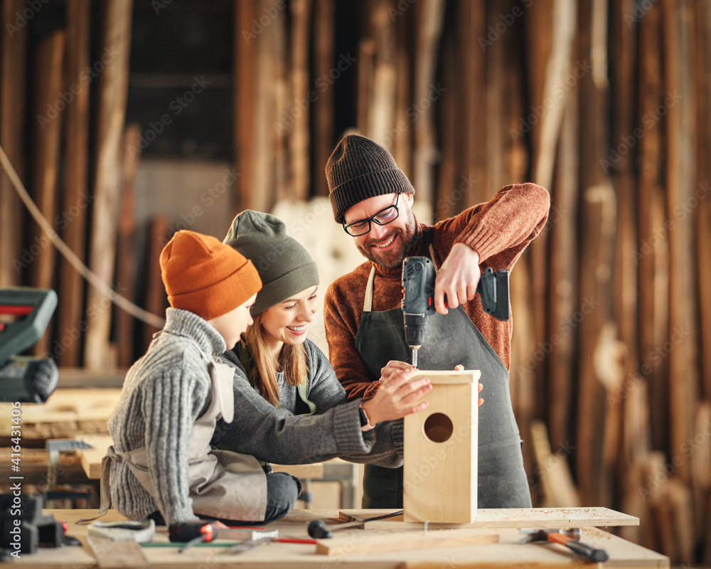 Kid with parents assembling wooden bird house in craft workshop - obrazy, fototapety, plakaty 