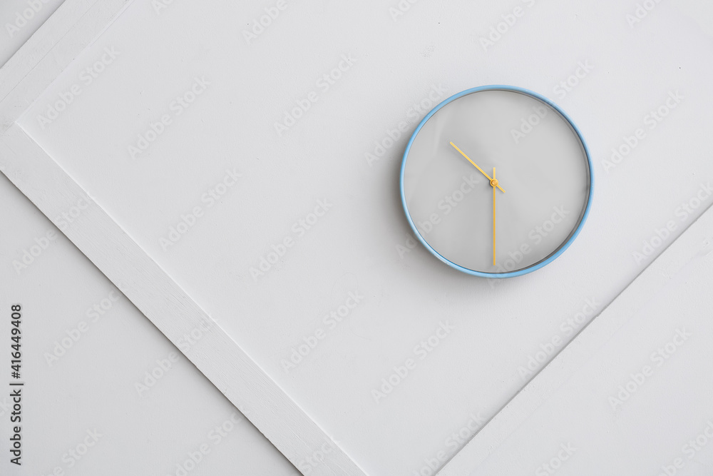 Stylish clock hanging on light wall