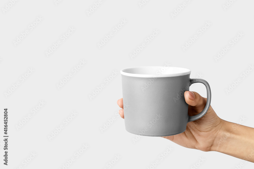 Hand with cup on light background