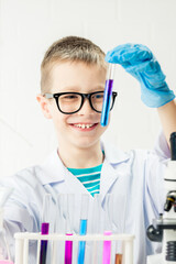 Wall Mural - a schoolboy studies multi-colored substances in test tubes, conducts experiments - a portrait on a w