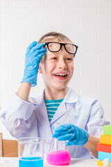 Wall Mural - a schoolboy studies multi-colored substances in test tubes, conducts experiments - a portrait on a w
