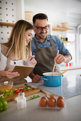 Wall Mural - Happy young couple enjoys and having fun preparing healthy meal together at home kitchen.