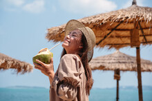 Portrait Image Of A Beautiful Asian Woman Holding A Fresh Coconut And Enjoying On The Beach
