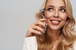 Happy gorgeous woman smiling while posing with eyelash curler